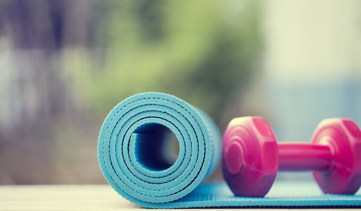 dumbbell and yoga mat on wood table